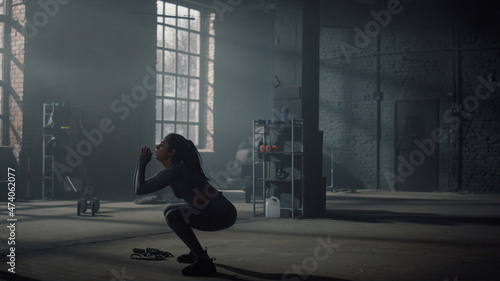 Girl doing squats with high jumps. Athlete practicing physical exercises 