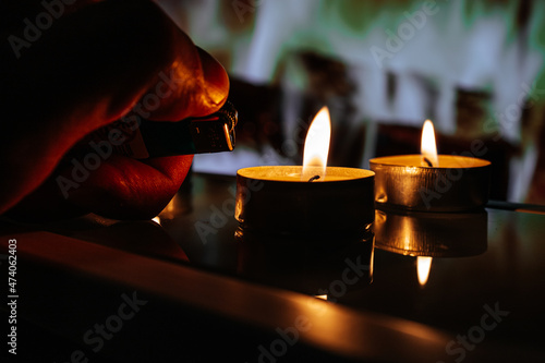 male hand lighting a candle with a lighter. blackout in Europe or Ukraine  photo