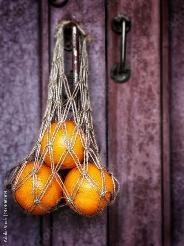 string bag with oranges hanging on an old rustic door selective focus