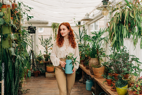 Gentle woman with jug of seedling in indoor garden