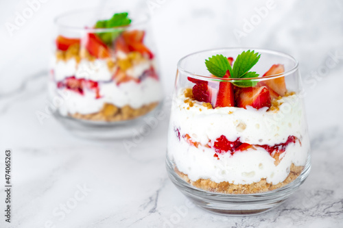 Fotografía Strawberry dessert with cream cheese or yogurt, granola and fresh strawberry in glass on marble background