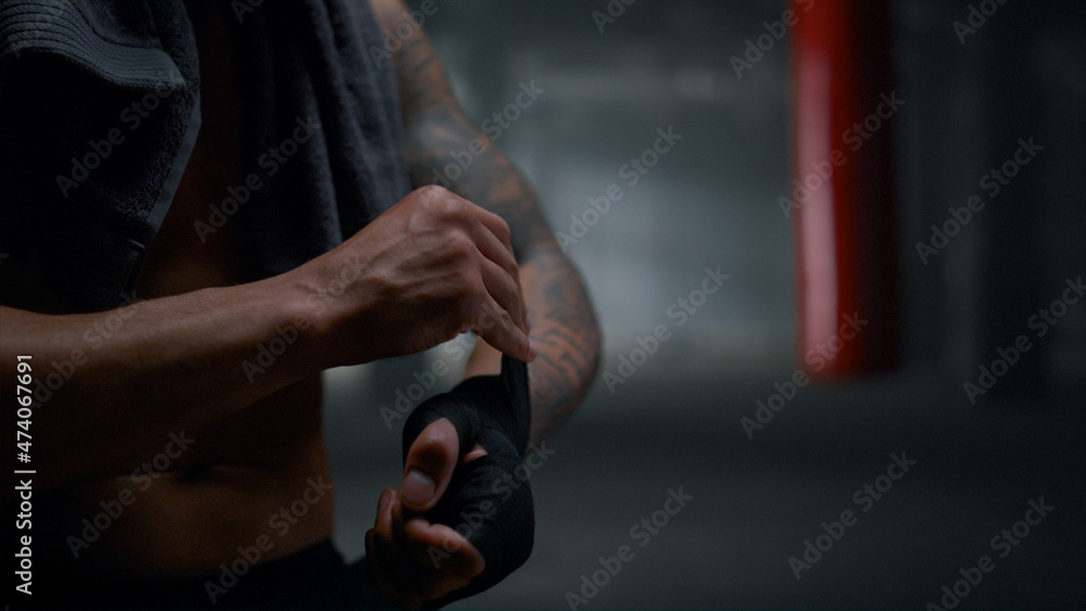 Man pulling bandages on hands. Guy wrapping hands with punching wraps