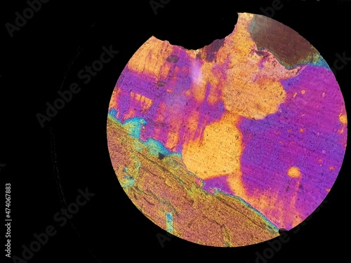 Beautiful colored sphere with vibrant colors in shades of purple and lilac with heart shape in orange color in the middle. Crystal seen under the microscope. Top view, abstract background. Black backg