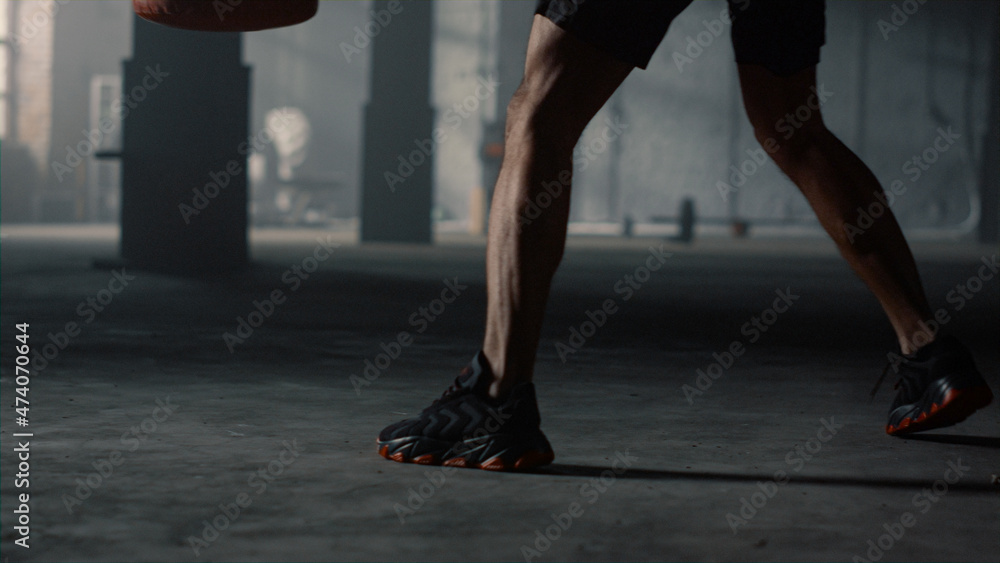 Guy legs moving during box training. Man practicing kickboxing with punch bag Guy legs moving during box training. Man practicing kickboxing with punch bag