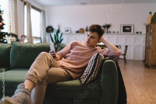 Caucasian man using smartphone on sofa at home