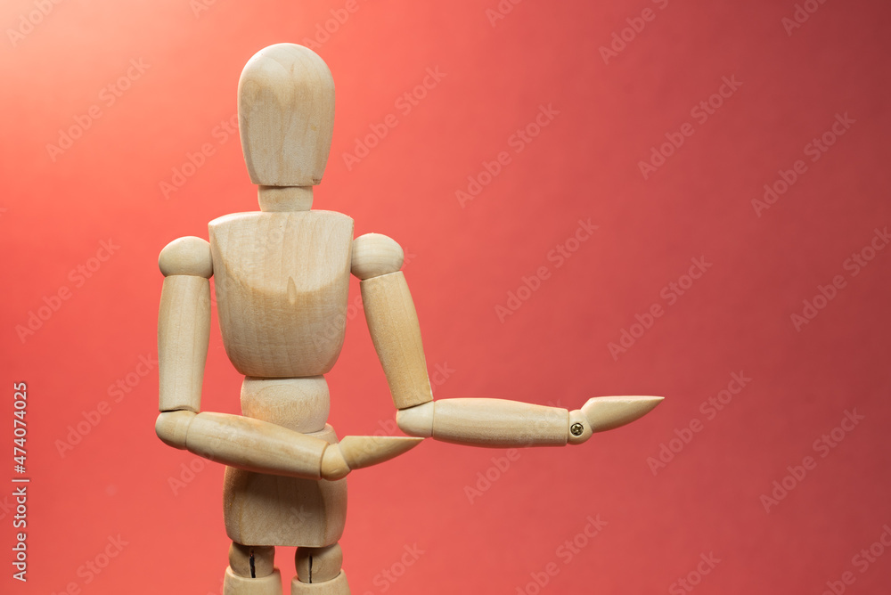 Wooden mannequin holding something, picture with free space to add your material, picture on red background Wooden mannequin holding something, picture with free space to add your material, picture on red background