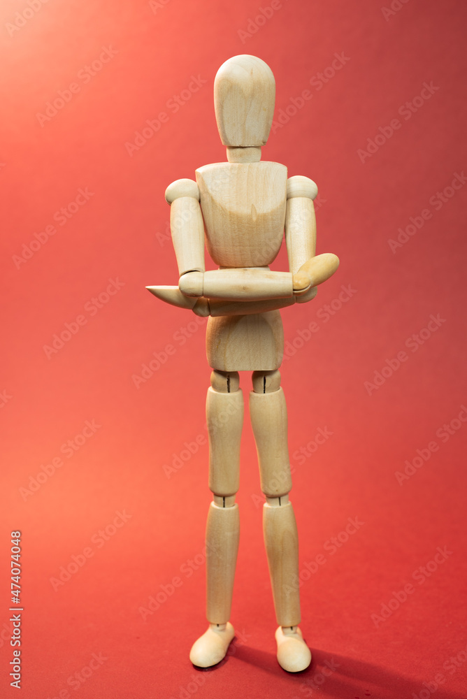 Wooden mannequin staying with crossed hands, arms, picture on red background Wooden mannequin staying with crossed hands, arms, picture on red background