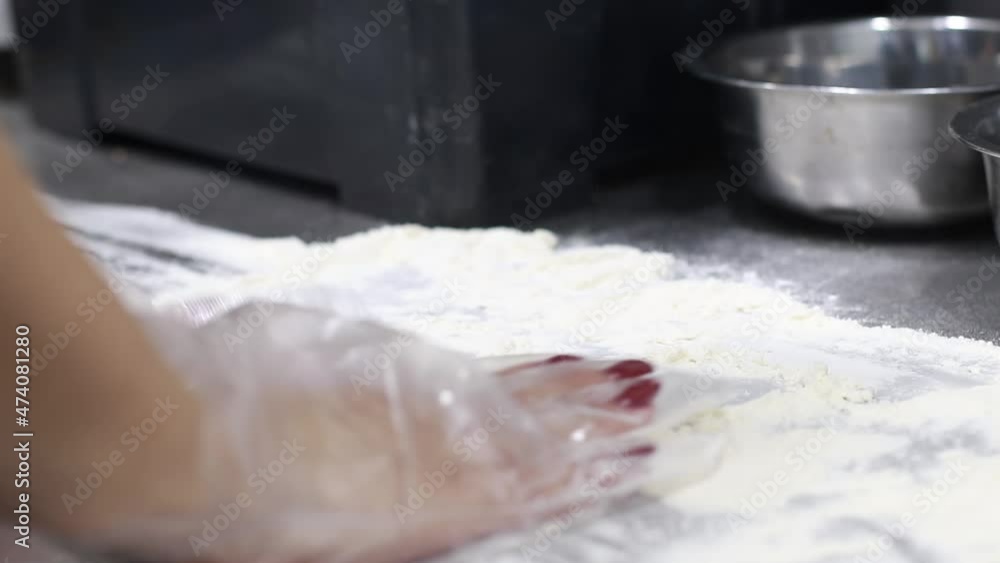 the cook distributes flour on the table, prepares the table for dough preparation the cook distributes flour on the table, prepares the table for dough preparation