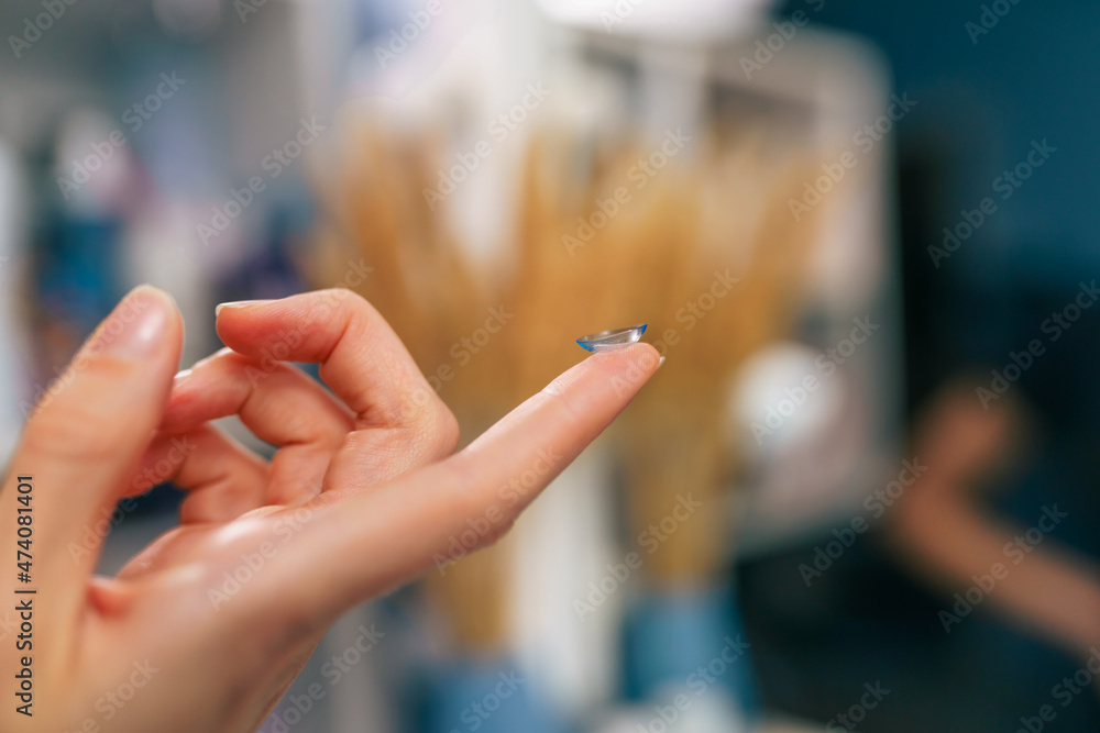 Transparent contact lens in the hands of a woman, preparing to insert it in her eyes