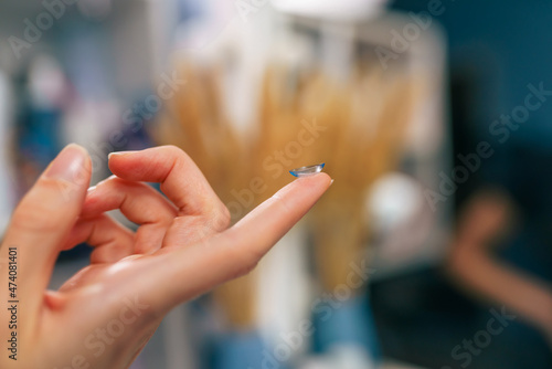 Transparent contact lens in the hands of a woman, preparing to insert it in her eyes