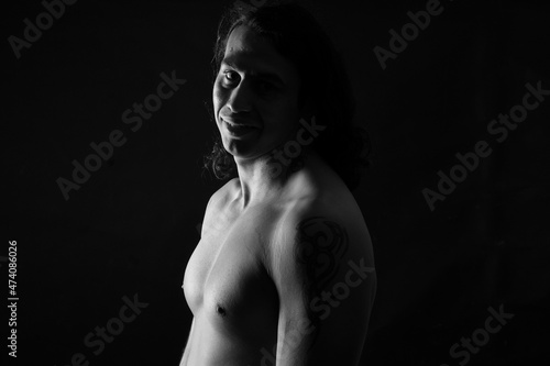 portrait of a man long hair in low key looking at camera and smiling on black background