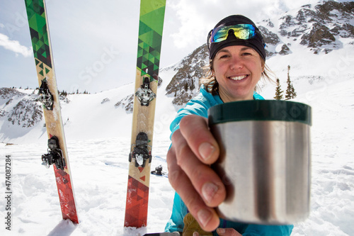 Woman offers tea while taking break from backcountry skiing.