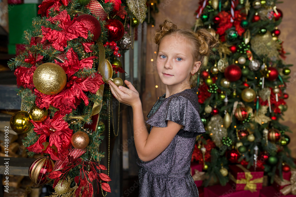 A little girl with a Christmas present. A girl near the Christmas tree.
