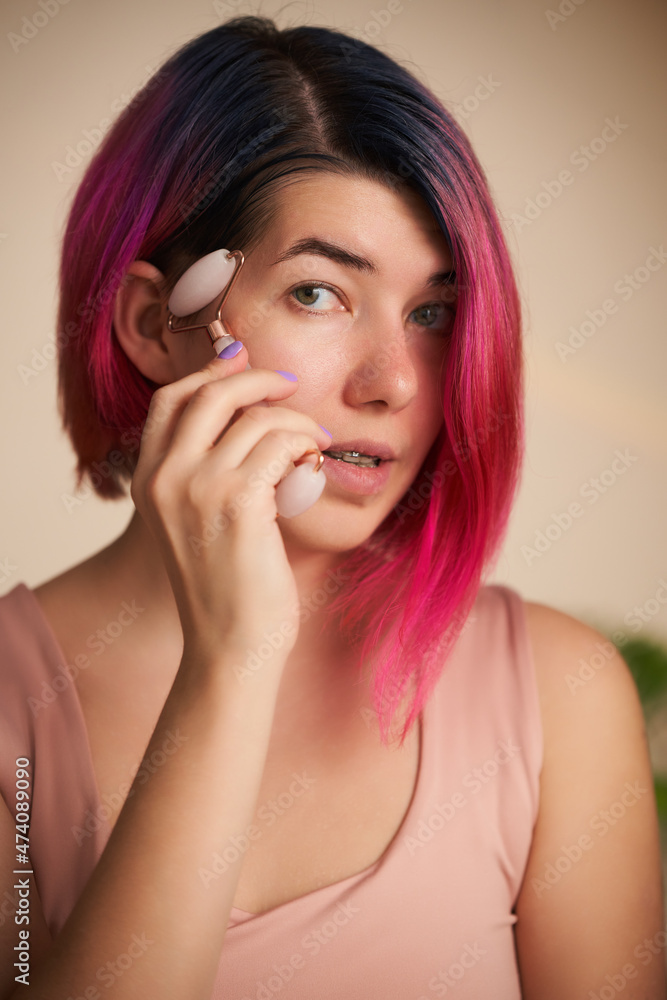 Woman is massaging her face roller.