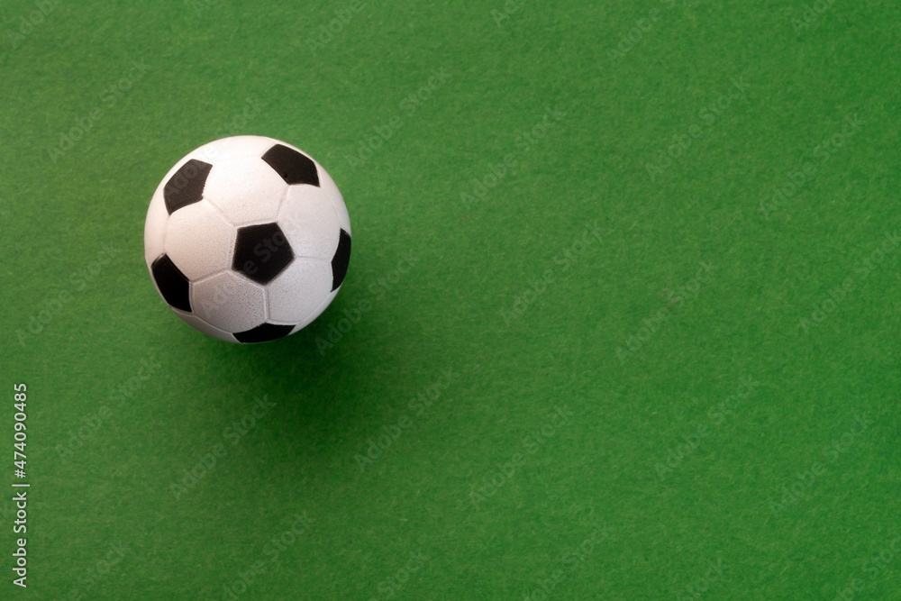 Toy soccer ball on the sheet of green paper