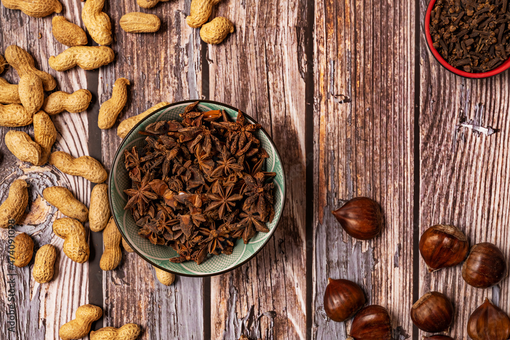 Top view image of bowl full of star anise, chestnuts and peanuts on wooden table Top view image of bowl full of star anise, chestnuts and peanuts on wooden table