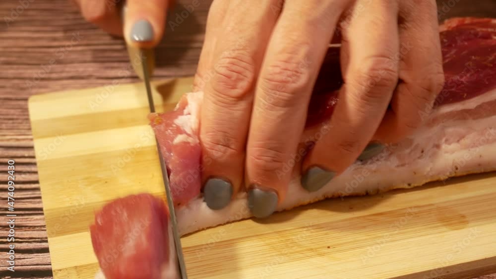 The cook cuts pieces of meat with lard on a cutting board. Cooking meat dishes The cook cuts pieces of meat with lard on a cutting board. Cooking meat dishes