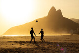Two Brothers Mountain behind 2 friends playing soccer at Ipanema Beach, Rio de Janeiro. Sunset at summer