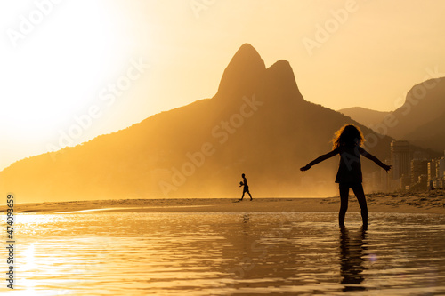 Kid playing on the water at Ipanema Beach, Brazil on a Sunset at summer. Two Brothers Mountain on background