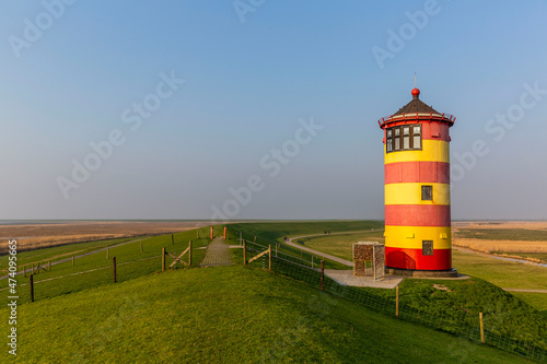 The striped red and yellow Pilsum lighthouse on the shores of the Wadden Sea in Germany
