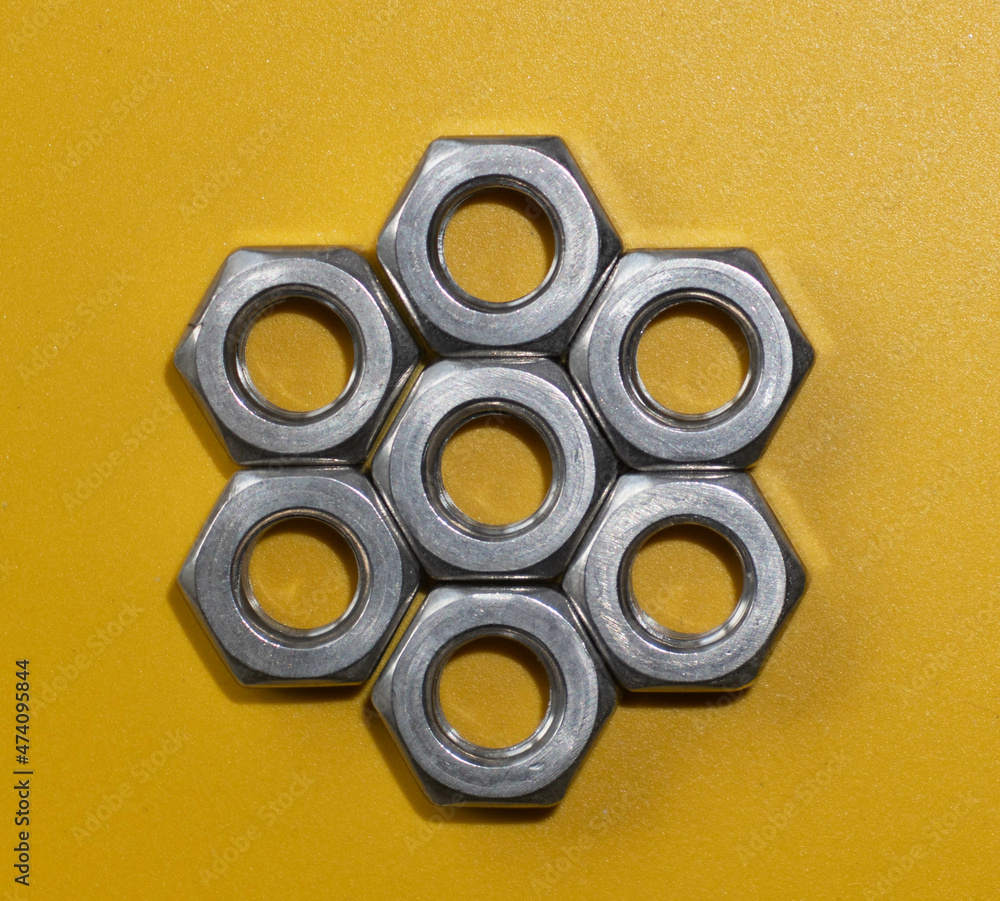Stainless nuts laid out on a colorful background in a hexagonal shape Stainless nuts laid out on a colorful background in a hexagonal shape