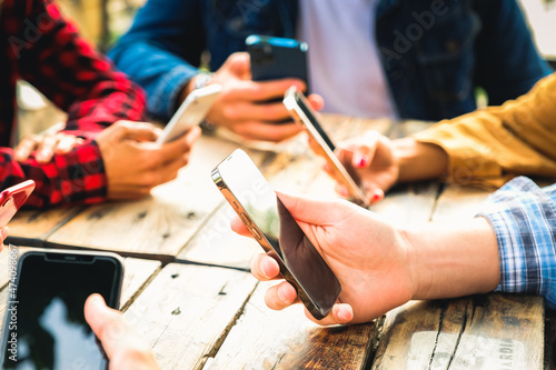 Group of friends checking social media on smartphones at restaurant or pub and ignoring each other - Close up of hands texting - Leisure, technology and people concept © damianobuffo