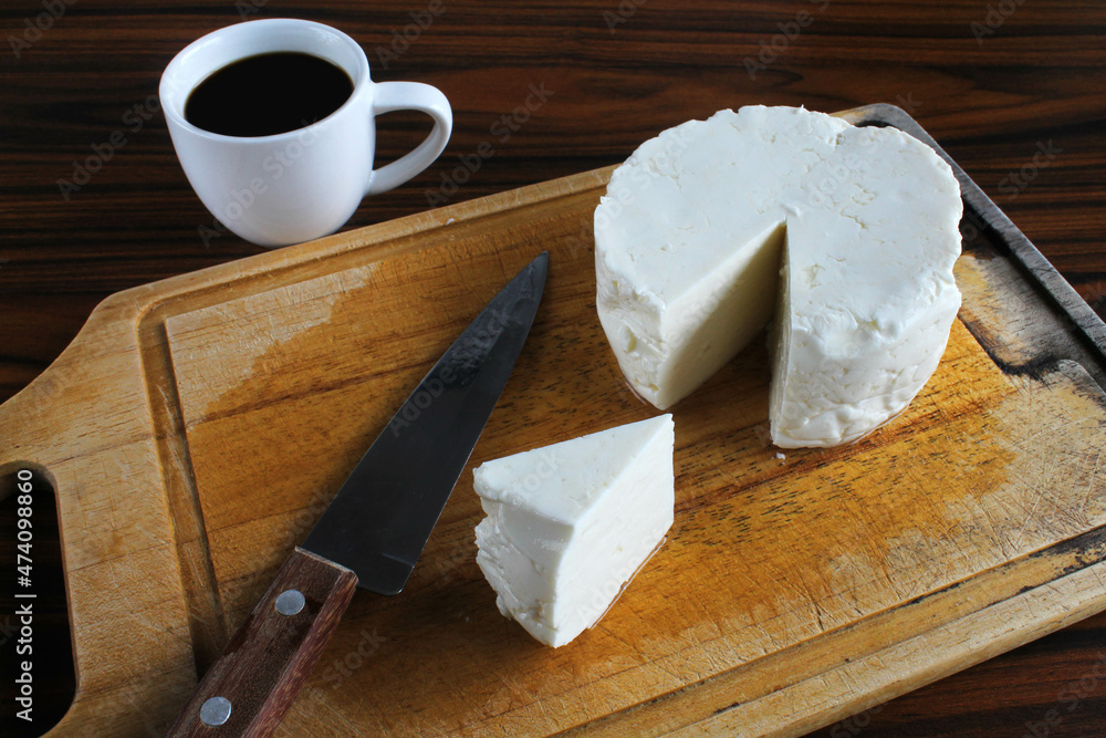 Cheese, white cheese called Minas cheese. Sliced white cheese with knife and cup of coffee.