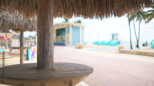 Miami Beach Florida boardwalk ocean background and closeup of tiki bar hut umbrella table empty with straw thatched roof at restaurant  photo
