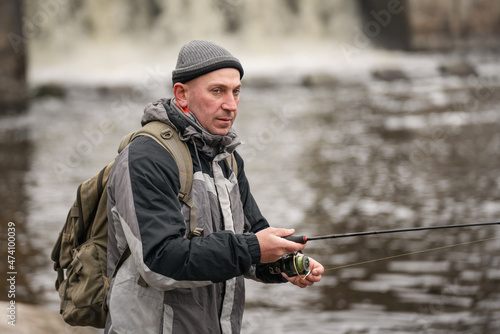 Man fishing on the river. Fisherman with a fishing rod on the background of water in cloudy weather