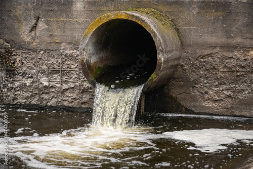 Foto Dirty water flows from the pipe into the river, environmental pollution