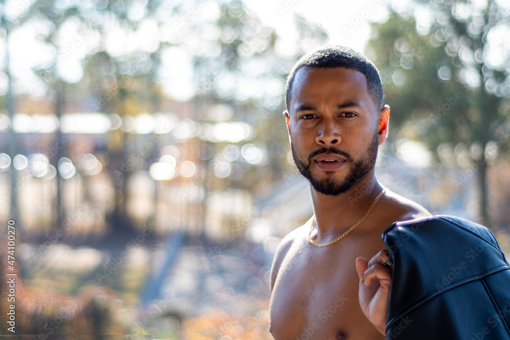Multi-racial athletic fit male shirtless holding leather jacket Multi-racial athletic fit male shirtless holding leather jacket