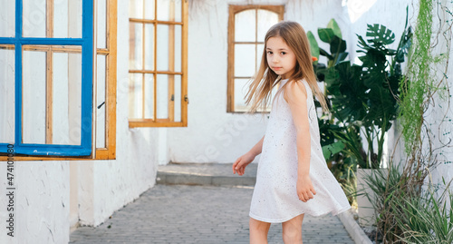 Beautiful girl with long hair in a white sundress in a light Balinese courtyard Greece Santorini vacation