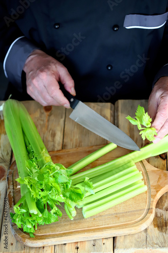 Selective focus. The cook cuts celery sticks with a knife. Fresh celery.