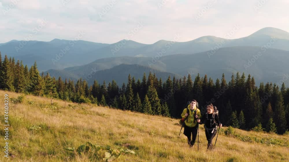 Couple of tourists walks up on hill. Majestic Carpathian Mountains. Beautiful landscape of untouched nature Couple of tourists walks up on hill. Majestic Carpathian Mountains. Beautiful landscape of untouched nature