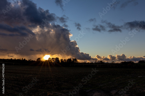 The Setting sun and storm clouds looking over a farmers field - stock photo.jpg