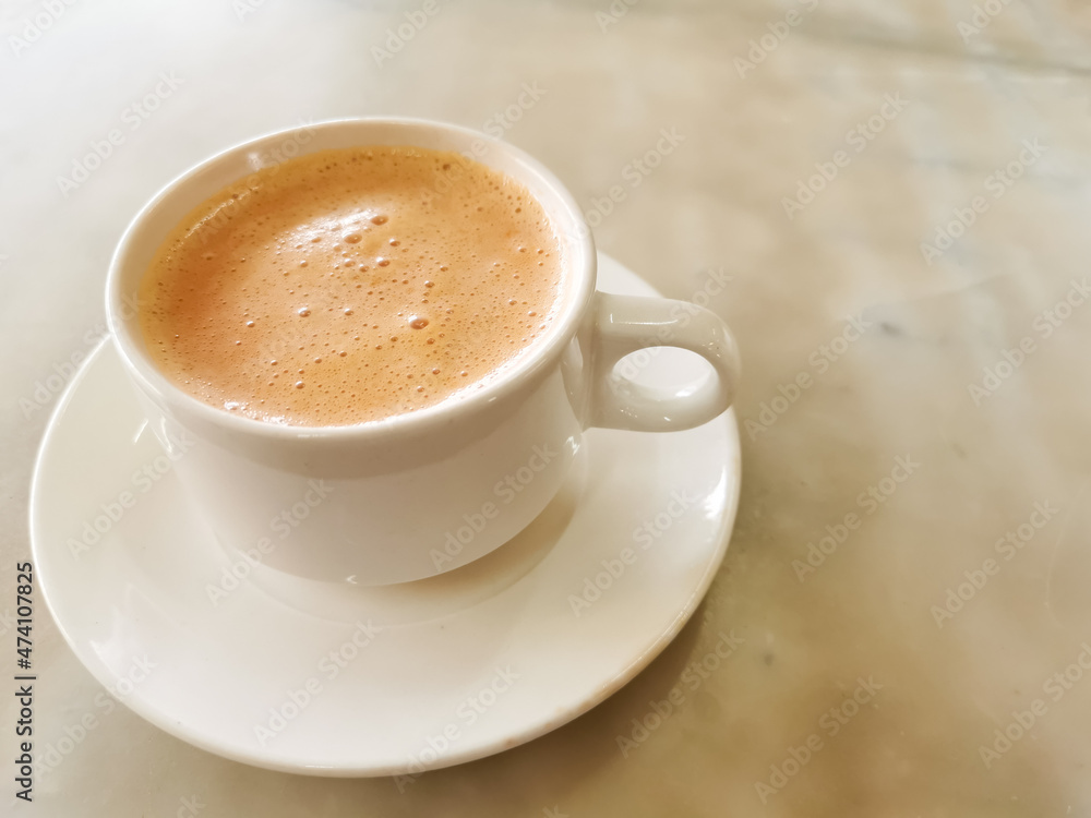 Tea with milk in a cup locally popularly known as Teh Tarik on the table. Tea with milk in a cup locally popularly known as Teh Tarik on the table.