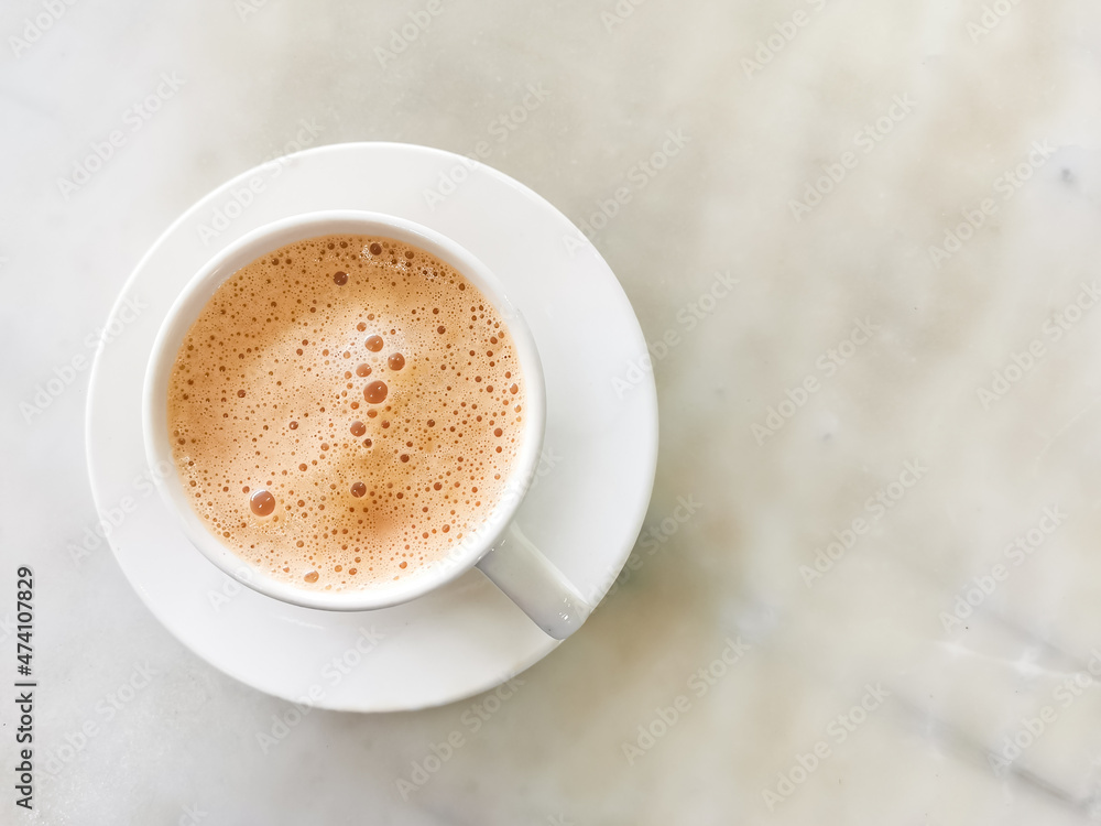 Tea with milk in a cup locally popularly known as Teh Tarik on the table. Tea with milk in a cup locally popularly known as Teh Tarik on the table.