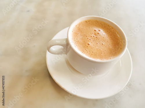 Tea with milk in a cup locally popularly known as Teh Tarik on the table.