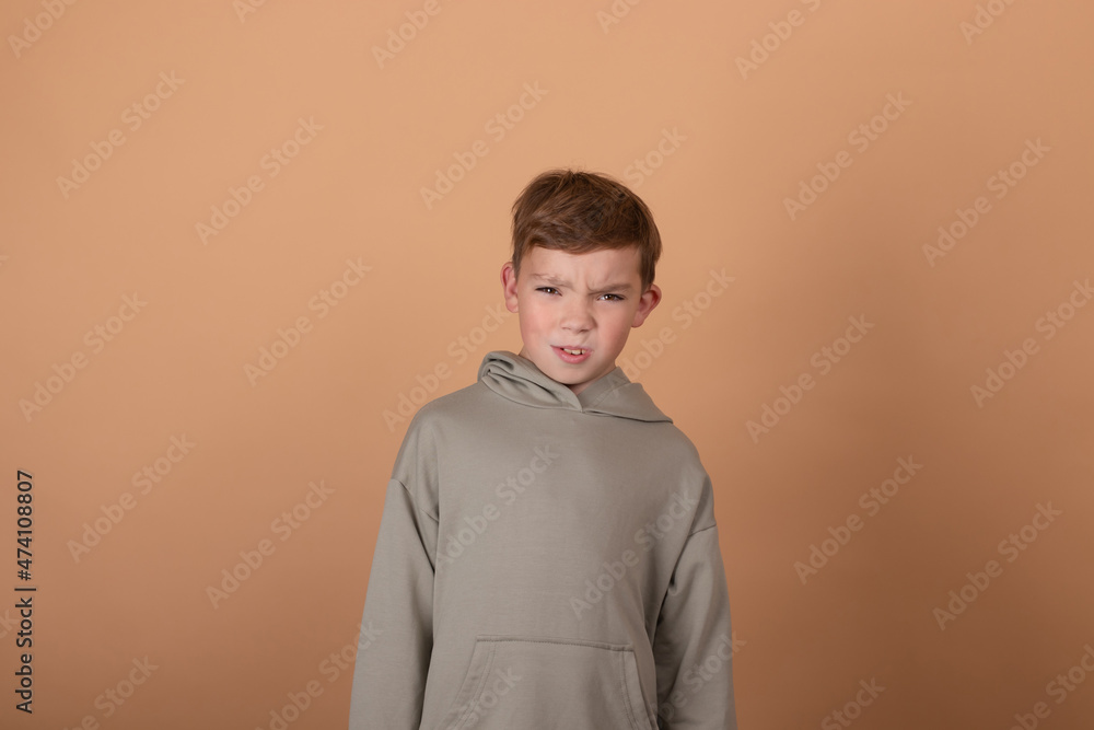 emotional portrait of a young boy teenager. charming school boy. beautiful kid. on light brown background. emotional portrait of a young boy teenager. charming school boy. beautiful kid. on light brown background.