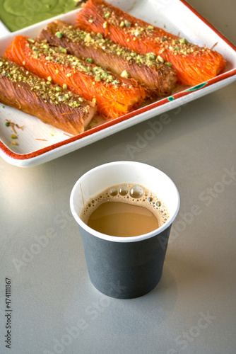 Turkish Coffee with sweets, kunafa rolls, with pistachio nuts on top on gray background