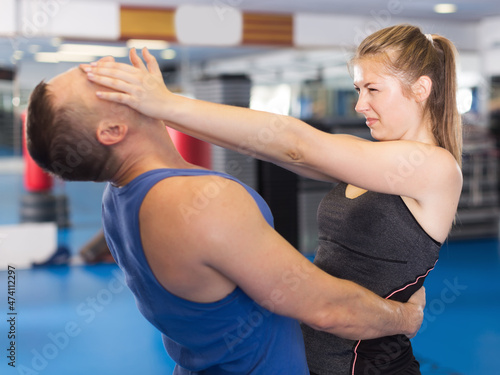 Sport woman and her trainer are exercise punches on the self-defense course in gym...