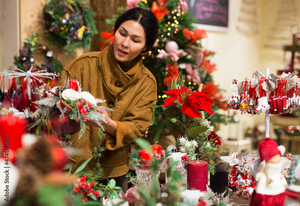 Asian woman who came to the store for shopping chooses a Christmas composition with candles