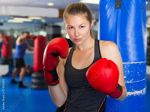 Portrait of young positive woman in red boxing gloves training in fitness center © JackF