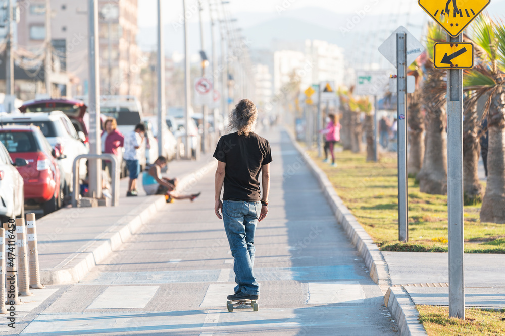 Obraz premium latin mature or senior man skateboard on bikeway in La Serena at sunset