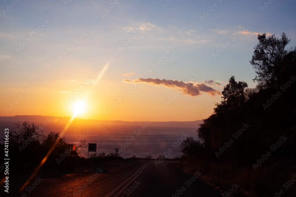 beautiful landscape in greek mountains: sunset ona road with sea line