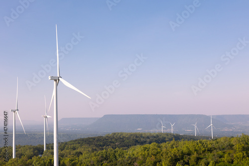 Many wind turbines in rows located with beautiful landscape on the hill with blue sky are operating to generate electric power which is the alternative energy resource for sustainable power supply.
