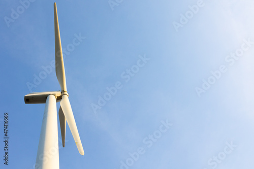 Looking up view of windmill or wind turbine under blue sky in the morning shows concept of renewable energy to supply and produce electricity for environmental friendly and green technology.