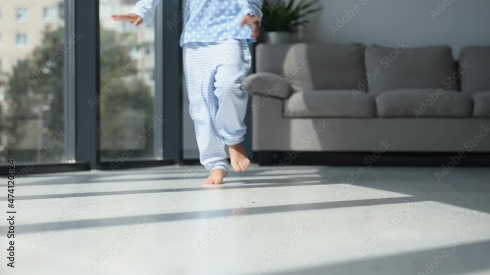 Runs forward. Close up view. Cute little girl in nightwear is home alone at daytime in modern room Runs forward. Close up view. Cute little girl in nightwear is home alone at daytime in modern room