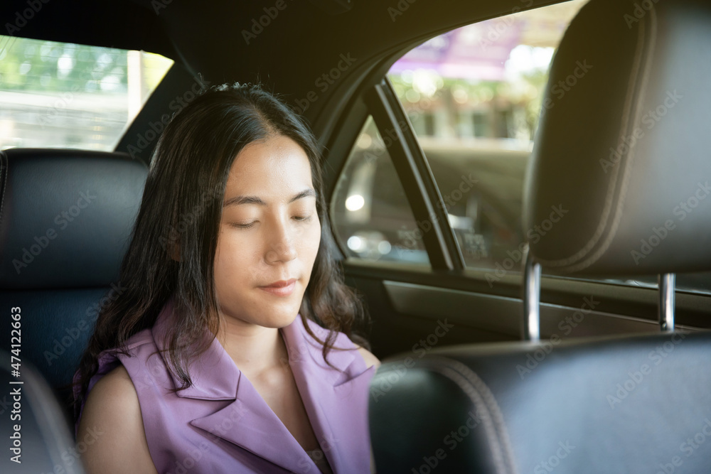 Asian young businesswoman travel by using a private taxi in the city, woman taking backseat.