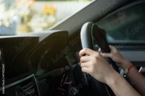 Asian young beautiful businesswoman sitting in her personal car in a driver seat and holding a steering wheel.